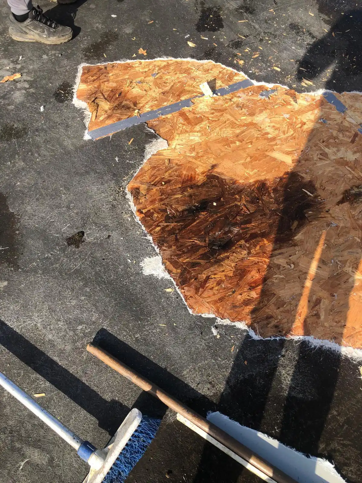 Partial view of a wooden board layout on a surface, with tools nearby. Shadows and debris are visible.